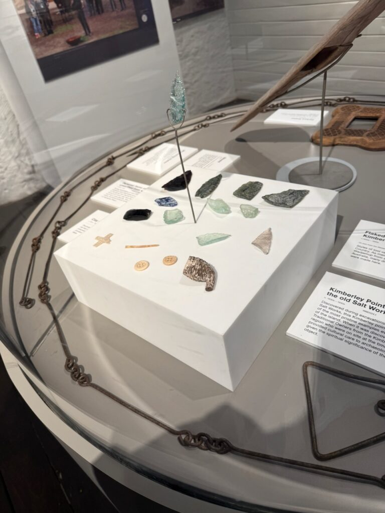 Glass display case in the museum showing glass spear heads, part of a clay pipe, a button and other artefacts from the time of the island's use as a prison