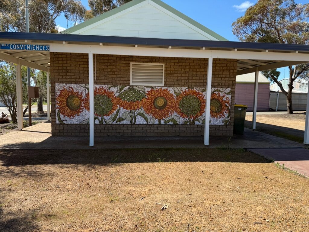 Flower tiled mural on the birick wall of the 'conveniences'