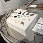 Glass display case in the museum showing glass spear heads, part of a clay pipe, a button and other artefacts from the time of the island's use as a prison