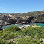 Bay surrounded by vegetation covered and sandy eroded limestone cliffs